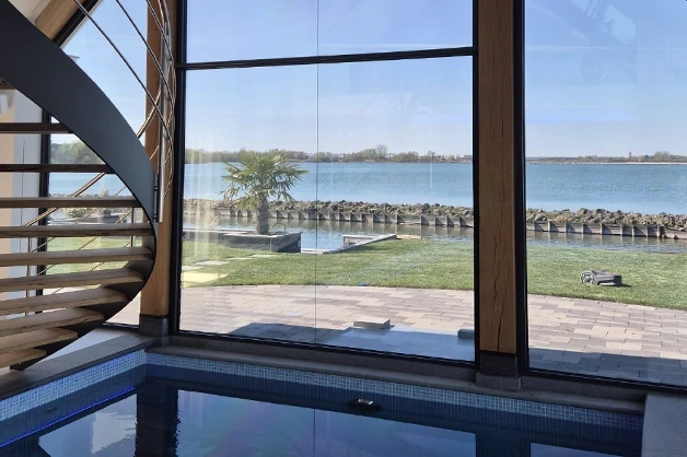 Uitzicht over het water vanuit woning met spiegelende raamfolie van Raamfolie Nederland op grote raampartijen